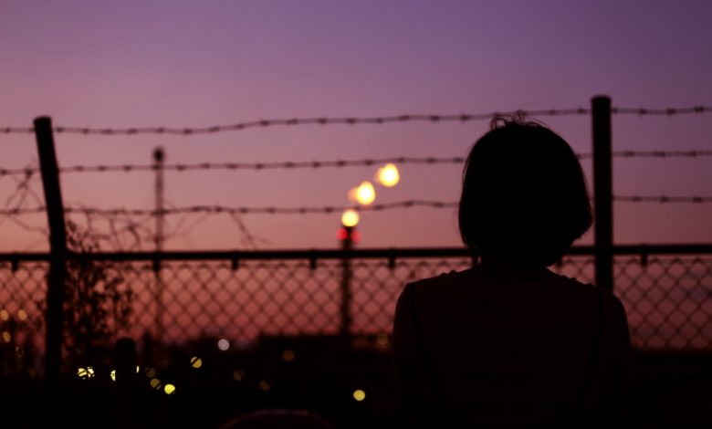 silhouette of person in front of fence