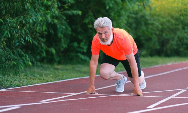 serious strong elderly man starting for run in racetrack