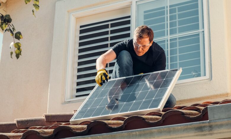 man with gloves holding solar panels on the roof